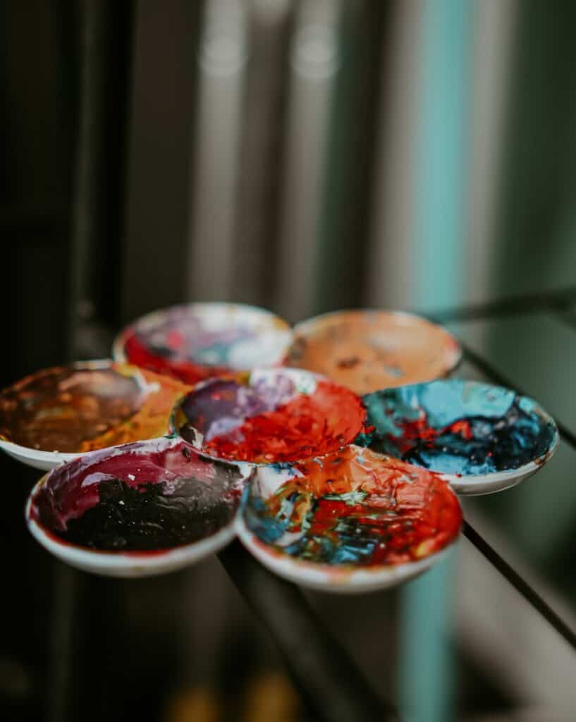 A row of bowls filled with paint sitting on top of a glass table