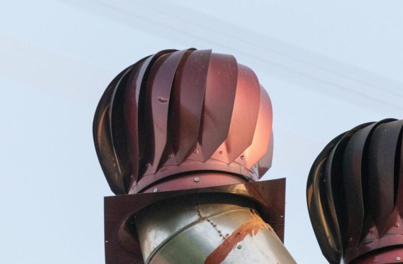 A detailed view of a rotating roof turbine ventilator against a clear sky in İzmir, Türkiye.