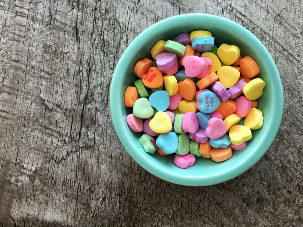assorted-color heart shape candies on teal bowl